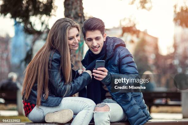 tiener paar in de stad samen browsen op de telefoon - 2017 common good forum stockfoto's en -beelden