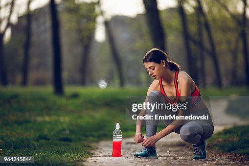 Young female runner tying shoelaces outdoors Young female runner tying shoelaces outdoors