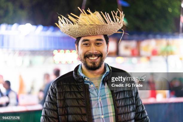 portrait of a brazilian man in the junina party at night (festa junina) - caipira style - straw hat stock pictures, royalty-free photos & images