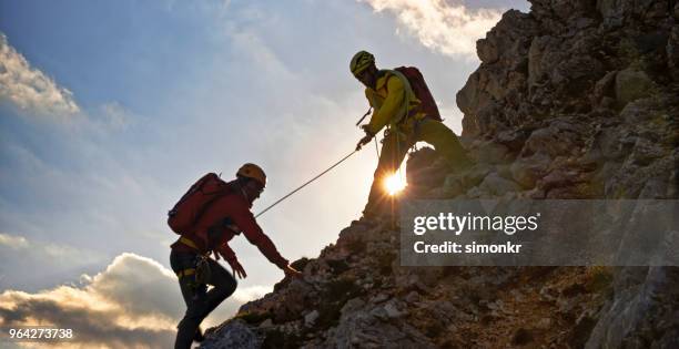 登山家の彼の友人を助ける - rope ストックフォトと画像