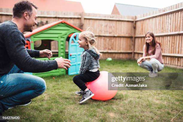 孩子彈跳在她的球和與她的父母在戶外玩耍 - hoppity horse 個照片及圖片檔