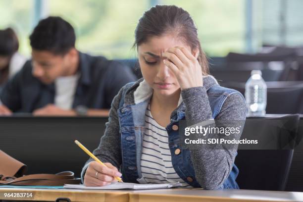 junge frau nimmt schwierige college prüfung - confused writing stock-fotos und bilder