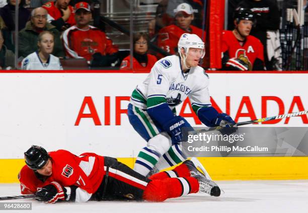 Filip Kuba of the Ottawa Senators gets knocked to the ice by Christian Ehrhoff of the Vancouver Canucks in a game at Scotiabank Place on February 4,...