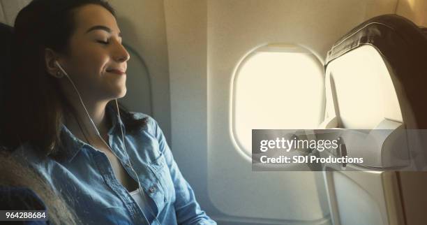 woman relaxes while flight on commercial airplane - window seat stock pictures, royalty-free photos & images