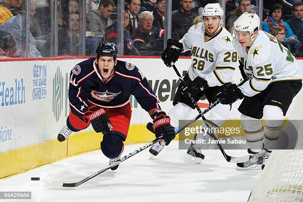 Jared Boll of the Columbus Blue Jackets loses his footing while attempting to keep the puck away from Mark Fistric and Warren Peters, both of the...