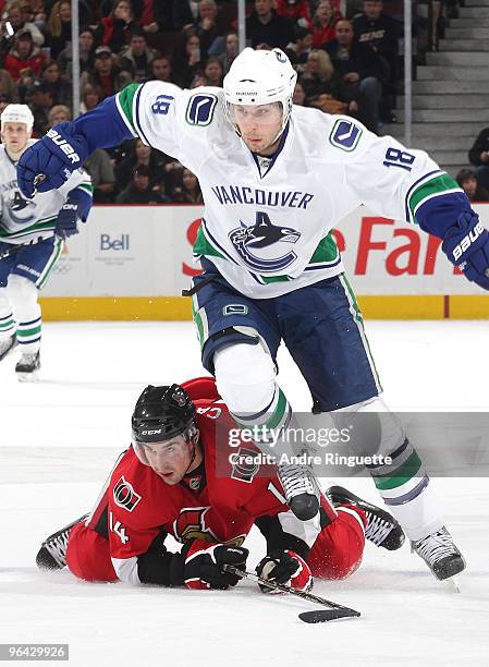 Steve Bernier of the Vancouver Canucks jumps over a fallen Chris Campoli of the Ottawa Senators for a loose puck at Scotiabank Place on February 4,...