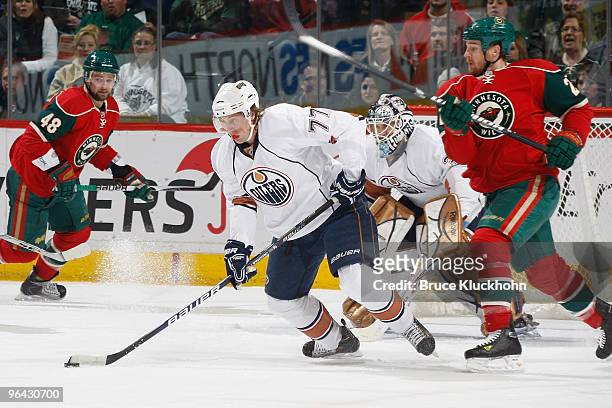 Tom Gilbert of the Edmonton Oilers skates with the puck with Kyle Brodziak of the Minnesota Wild defending during the game at the Xcel Energy Center...