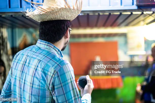 mann schießen dosen mit kugeln spiel in der traditionellen brasilianischen junina partei - ball werfen stock-fotos und bilder