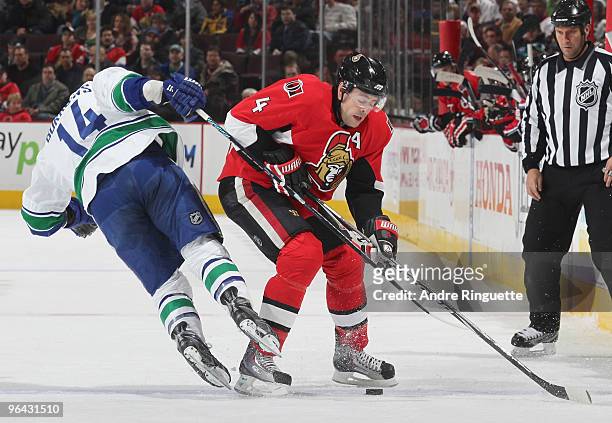 Chris Phillips of the Ottawa Senators keeps the puck inside the blue line as Alex Burrows of the Vancouver Canucks loses his footing at Scotiabank...