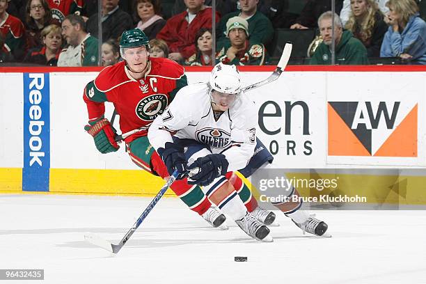 Denis Grebeshkov of the Edmonton Oilers skates with the puck while Mikko Koivu of the Minnesota Wild defends during the game at the Xcel Energy...