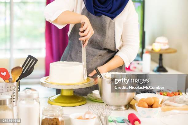 muslimischen haus bäcker vereisung eine geschichtete schokoladentorte mit buttercreme - beautiful women spreading stock-fotos und bilder