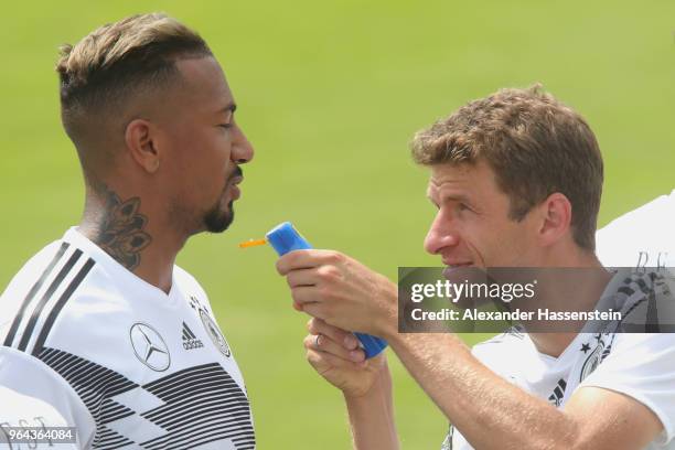 Thomas Mueller jokes with a bottle of sun cream to his team mate Jerome Boateng during a training session of the German national team at Sportanlage...