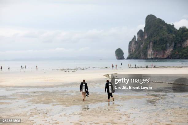 Divemasters Kristina Washer, left, and Kathryn Jacobus walk on a beach with diving equipment on April 30, 2018 in Ko Phi Phi Don, Thailand.