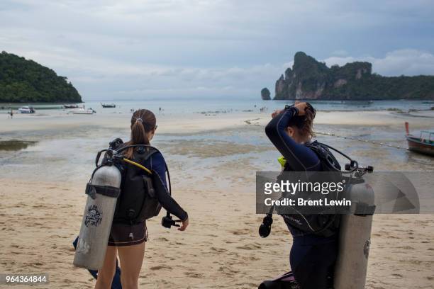 Divemasters Kristina Washer, left, and Kathryn Jacobus stand on a beach with diving equipment on April 30, 2018 in Ko Phi Phi Don, Thailand.