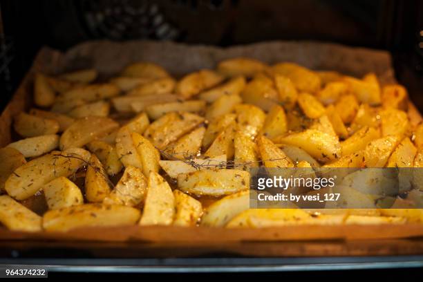 potatoes with herbs roasting in the oven - frite four photos et images de collection
