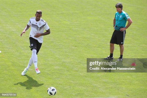 Jerome Boateng runs with the ball next to Joachim Loew, head coach of Germany during a training session of the German national team at Sportanlage...