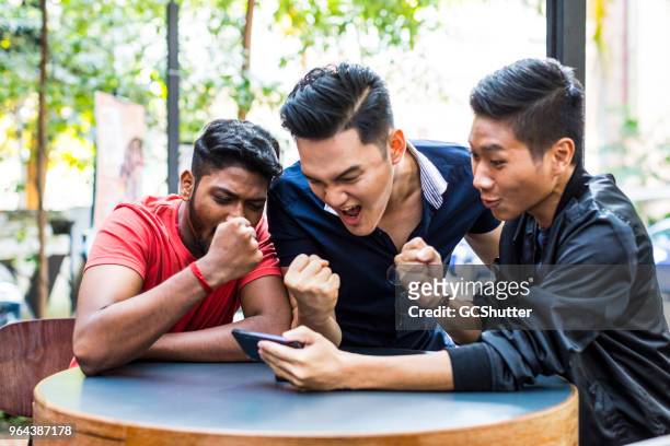 group of friends watching their favorite match on a mobile phone - jogos de azar imagens e fotografias de stock