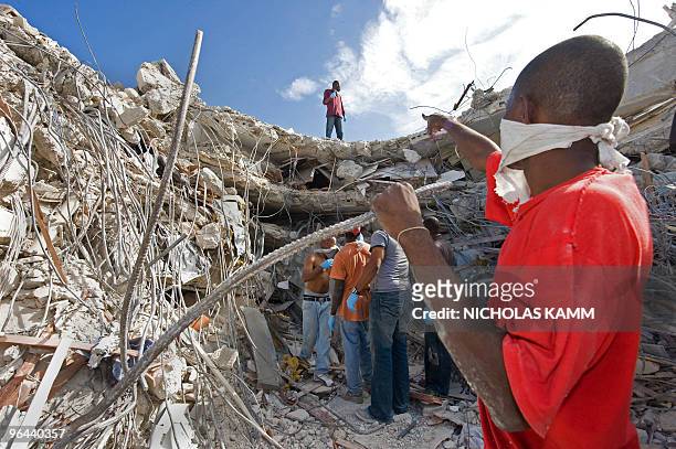 Tax authority employees aid in freeing a colleague trapped in their collapsed building in Port-au-Prince on January 14 two days after an earthquake...