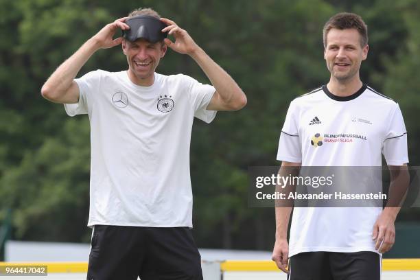 Thomas Mueller smiles with Alexander Fangmann during a Blind Football demonstration match with national players of the German national Blind Football...