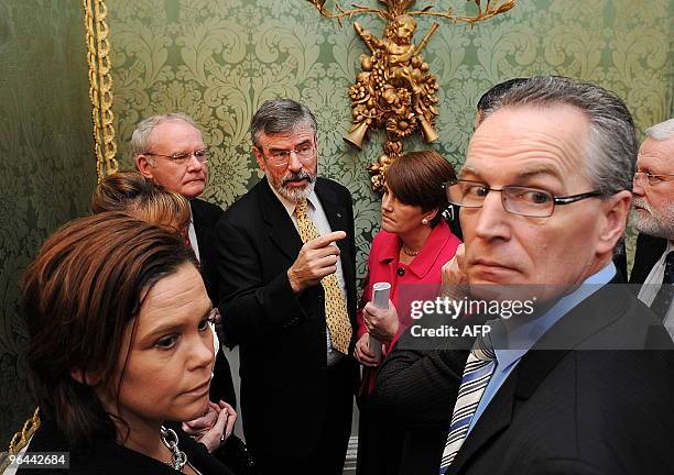 Sinn Fein President Gerry Adams talks to his party members following a press conference attended by Northern Ireland's First Minister Peter Robinson,...