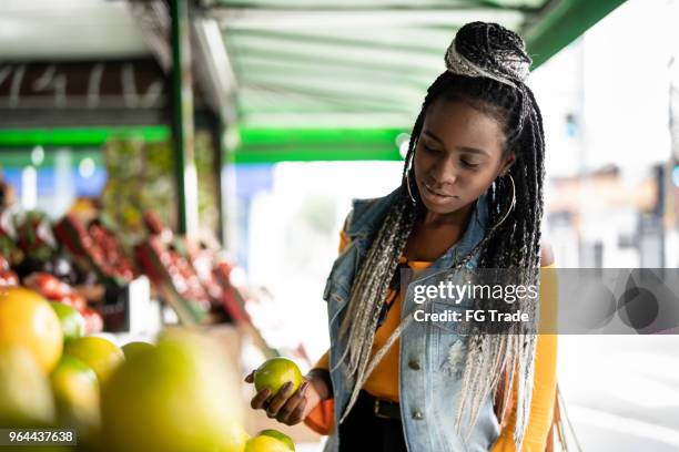 frau wahl früchte auf flohmarkt - african woman shopping stock-fotos und bilder