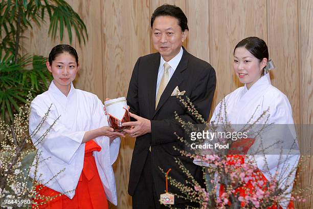 Japanese Prime Minister Yukio Hatoyama, center, smiles with "plum mission" shrine maidens, Yuko Kuramitsu, left, and Emiko Inoue, upon receiving a...
