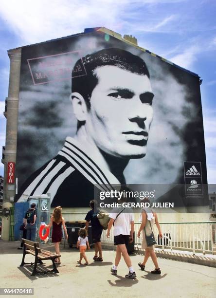 Des personnes passent devant le portrait géant de Zinedine Zidane, le 08 août 2000 à Marseille. Le footballeur Zinedine Zidane, héros du Mondial 98...