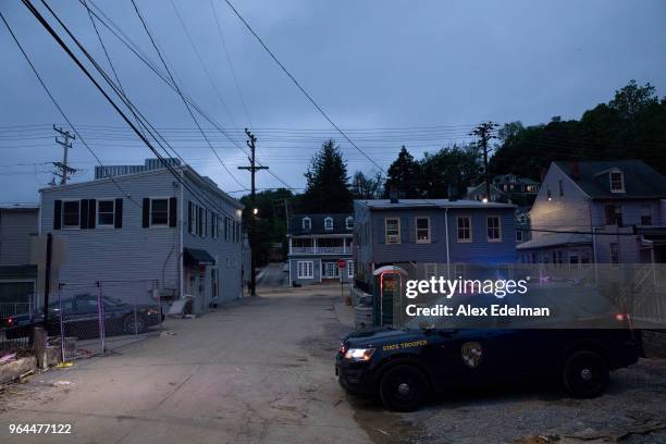Maryland State Police Trooper guards an entrance to Main Street as work crews work to secure structures several days after devastating flash flooding...