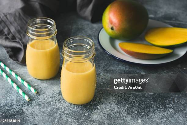 mango smoothie in bottle on concrete background - mango juice stockfoto's en -beelden