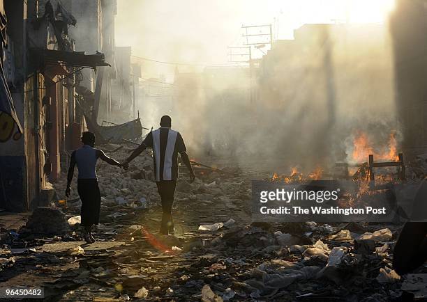 Haitians burn debris from the earthquake damage as people take goods from destroyed stores in the marketplace on January 18, 2010 Port-au-Prince,...