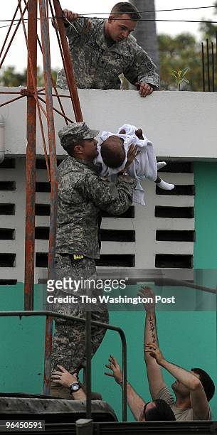 Soldiers from the U.S. 82nd Airborne assisted with transport handing the baby down from a roof on January 25, 2010 in Port-au-Prince, Haiti. A baby...