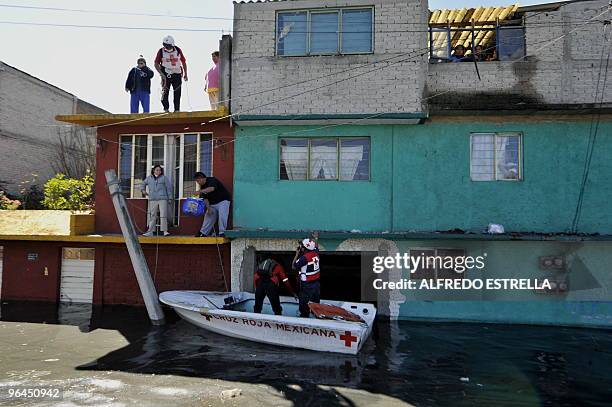 Members of the Mexican Red Cross help residents of the flooded Valle de Chalco community in the state of Mexico to evacuate their home, on February...