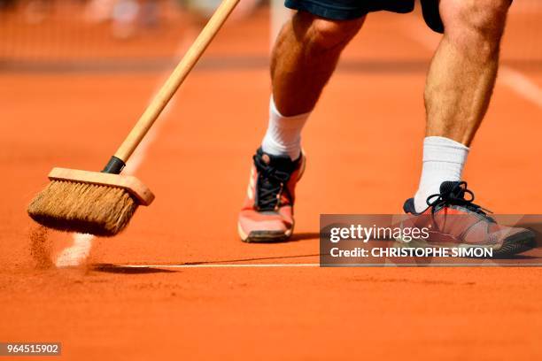 Groundstaff member sweeps the court between games during the women's singles second round match between Russia's Maria Sharapova and Croatia's Donna...