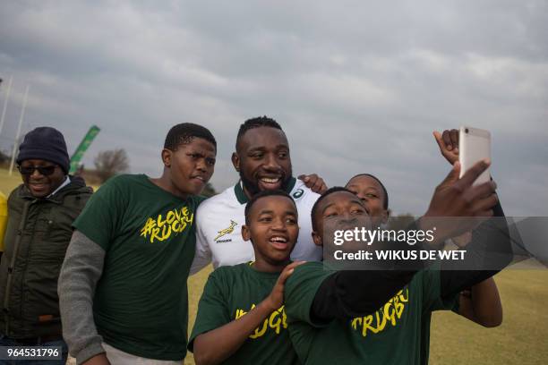 South Africa national Springbok player Tendai Mtawarira poses with aspiring rugby players from nearby high schools during a rugby clinic coaching...