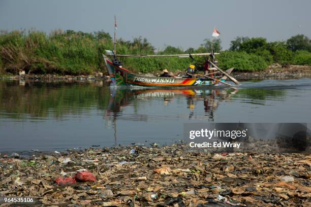 Fishermen return to there village along the coast which has been inundated with plastic trash on the northern coast on May 31, 2018 in Jakarta,...