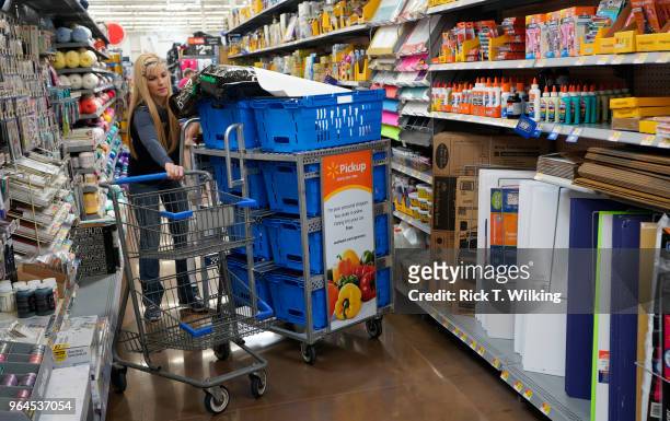 Walmart associate moves her pickup cart through an aisle at a Walmart Supercenter during the annual shareholders meeting event on May 31, 2018 in...