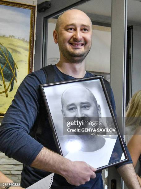 Anti-Kremlin journalist Arkady Babchenko holds a portrait of him that his colleagues displayed in his memory in the offices of his workplace, the ATR...