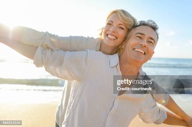 mature couple playing on the beach at sunset or sunrise. - backlit stock pictures, royalty-free photos & images