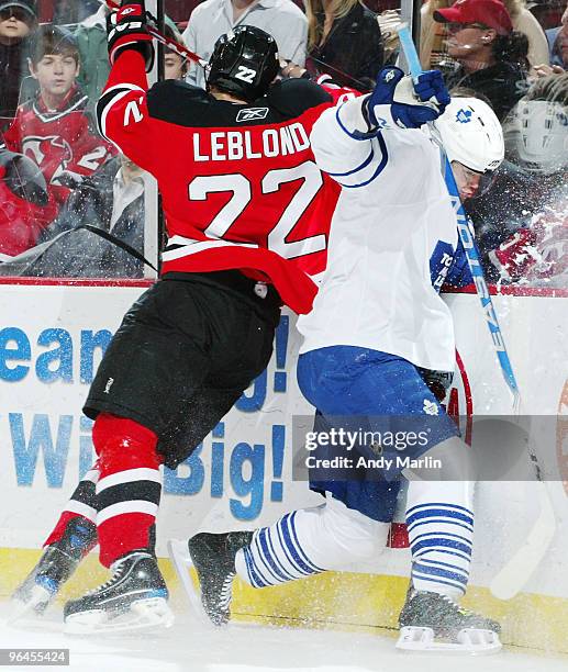 Garnet Exelby of the Toronto Maple Leafs and Pierre-Luc Letourneau-Leblond of the New Jersey Devils come together hard against the boards during the...