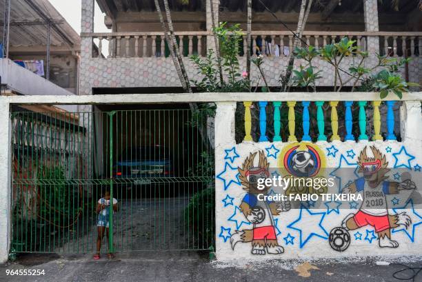 Girl is seen behind a gate next to a graffiti related to the 2018 World Cup, in Camboata neighbourhood in Rio de Janeiro, Brazil, on May 31, 2018.