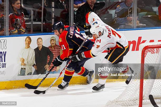 Adam Pardy of the Calgary Flames attempts to take the puck away from Gregory Campbell of the Florida Panthers on February 5, 2010 at the BankAtlantic...