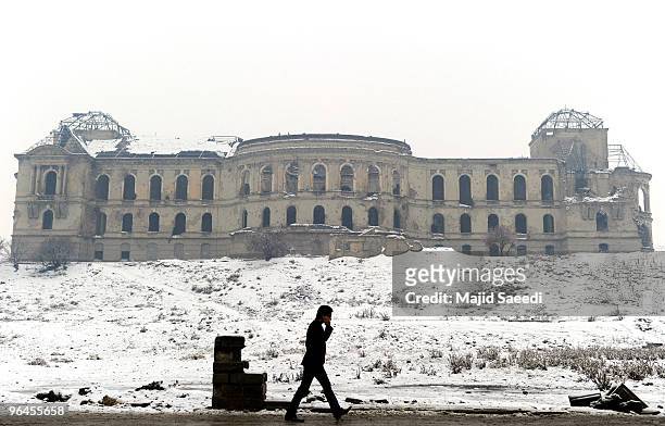 An Afghan walks past the destroyed Darul-Aman palace in the snow February 2010 in Kabul, Afghanistan.
