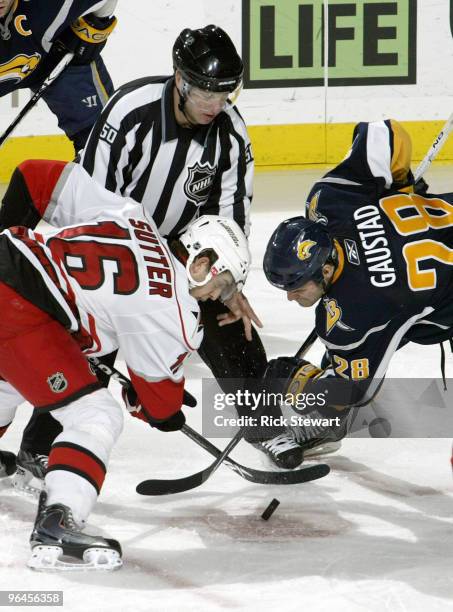 Brandon Sutter of the Carolina Hurricanes and Paul Gaustad of the Buffalo Sabres face off on the drop by linesman Scott Cherrey at HSBC Arena on...