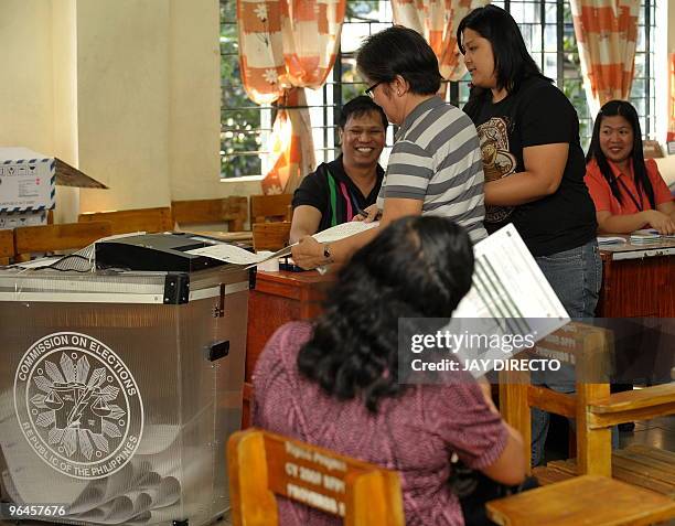 Voter in Quezon City, in suburban Manila, feeds her ballots in to a automated counting machine during a mock election intended to test the automated...