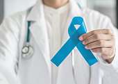 Blue ribbon symbolic for prostate cancer awareness campaign and men's health in doctor's hand
