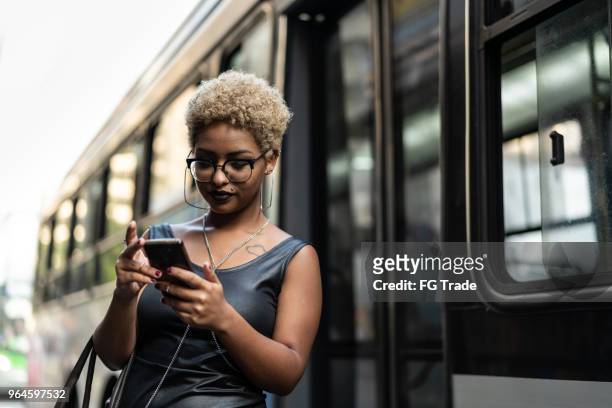 young woman checking the boarding time for the bus - waiting bus stock pictures, royalty-free photos & images