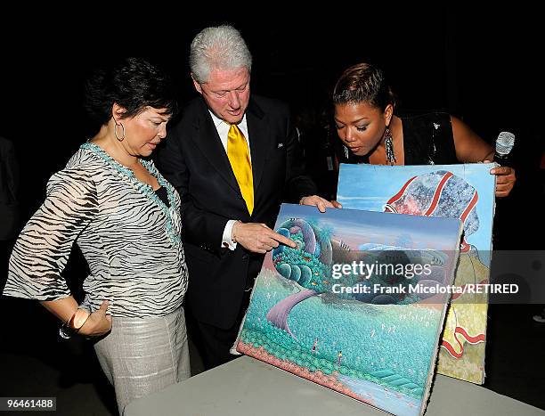 Debra Lee, Chairman & CEO of BET, former President Bill Clinton, and actress Queen Latifah look at Haitian paintings backstage at the BET SOS Saving...