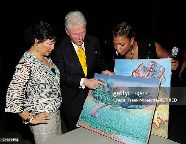 Debra Lee, Chairman & CEO of BET, former President Bill Clinton, and actress Queen Latifah look at Haitian paintings backstage at the BET SOS Saving...
