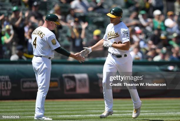 Matt Olson of the Oakland Athletics is congratulated by third base coach Matt Williams after Olson hit a solo home run against the Tampa Bay Rays in...