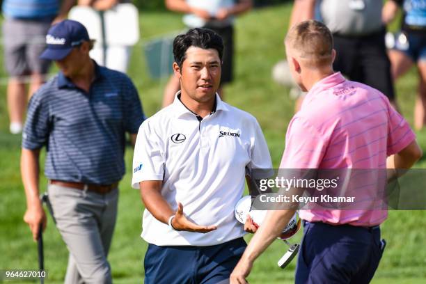 Hideki Matsuyama of Japan shakes hands Russell Knox of Scotland after finishing play on the 18th hole green during the first round of the Memorial...